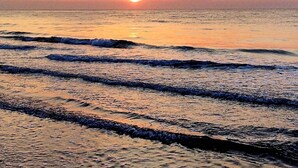 Une plage au coucher du soleil, avec des vagues qui se rapprochent du rivage.