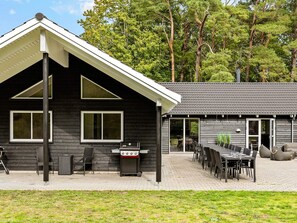 A modern building with a patio area, outdoor seating, and a grill. - 5 Star Holiday Home in Frederiksvaerk (Frederiksvaerk)