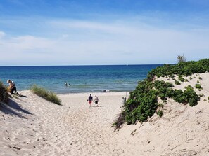 A beach with people walking and swimming, sandy terrain, and a clear sky. - 5 Star Holiday Home in Frederiksvaerk (Frederiksvaerk)