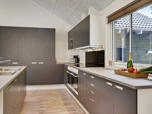 A modern kitchen with a built-in oven, a coffee maker, and a bottle of champagne on the counter. - 5 Star Holiday Home in Frederiksvaerk (Frederiksvaerk)