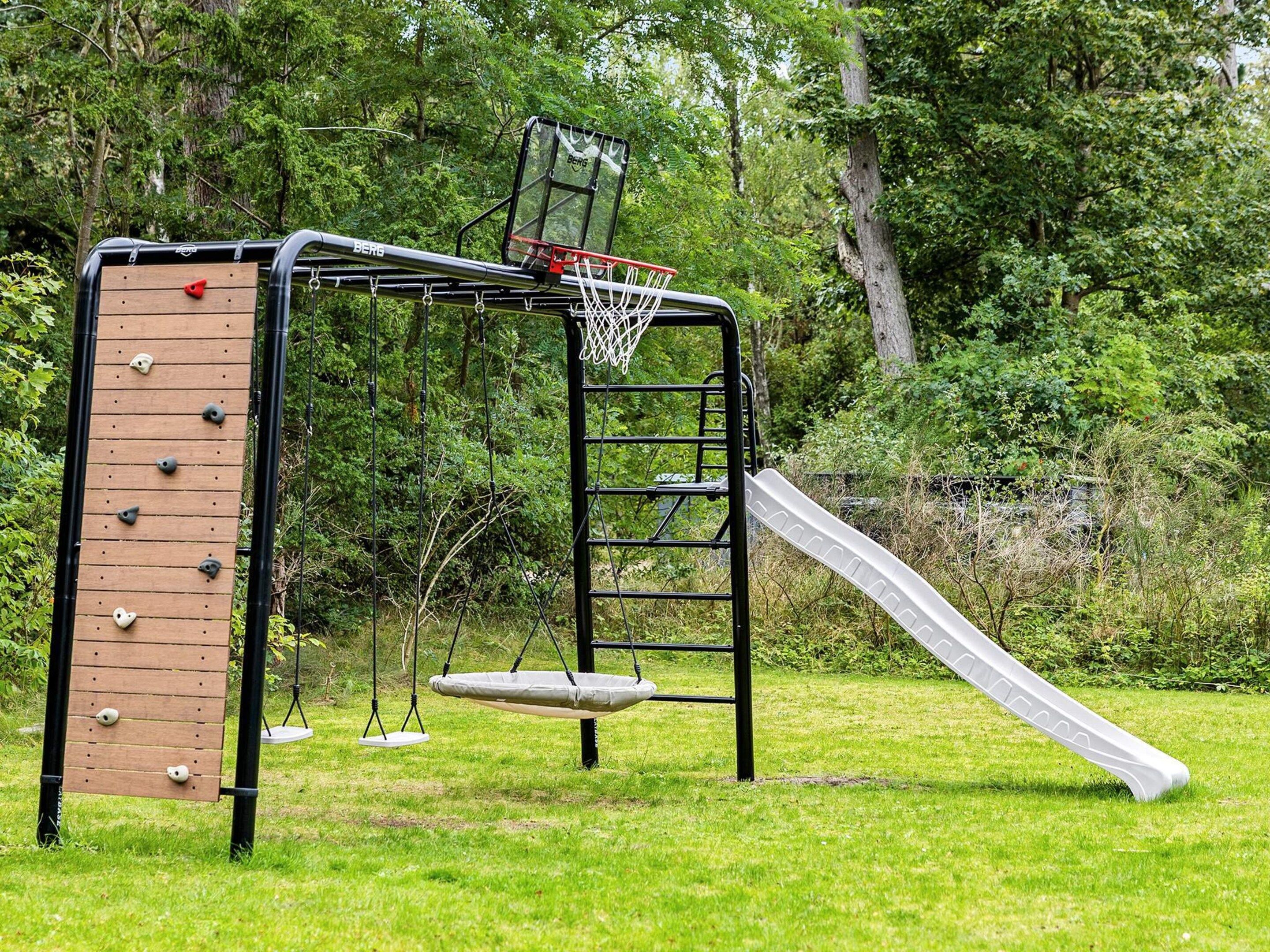 Une aire de jeux avec un mur d’escalade, un toboggan et une balançoire.