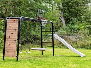 A playground with a climbing wall, a slide, and a swing set. - 5 Star Holiday Home in Frederiksvaerk (Frederiksvaerk)