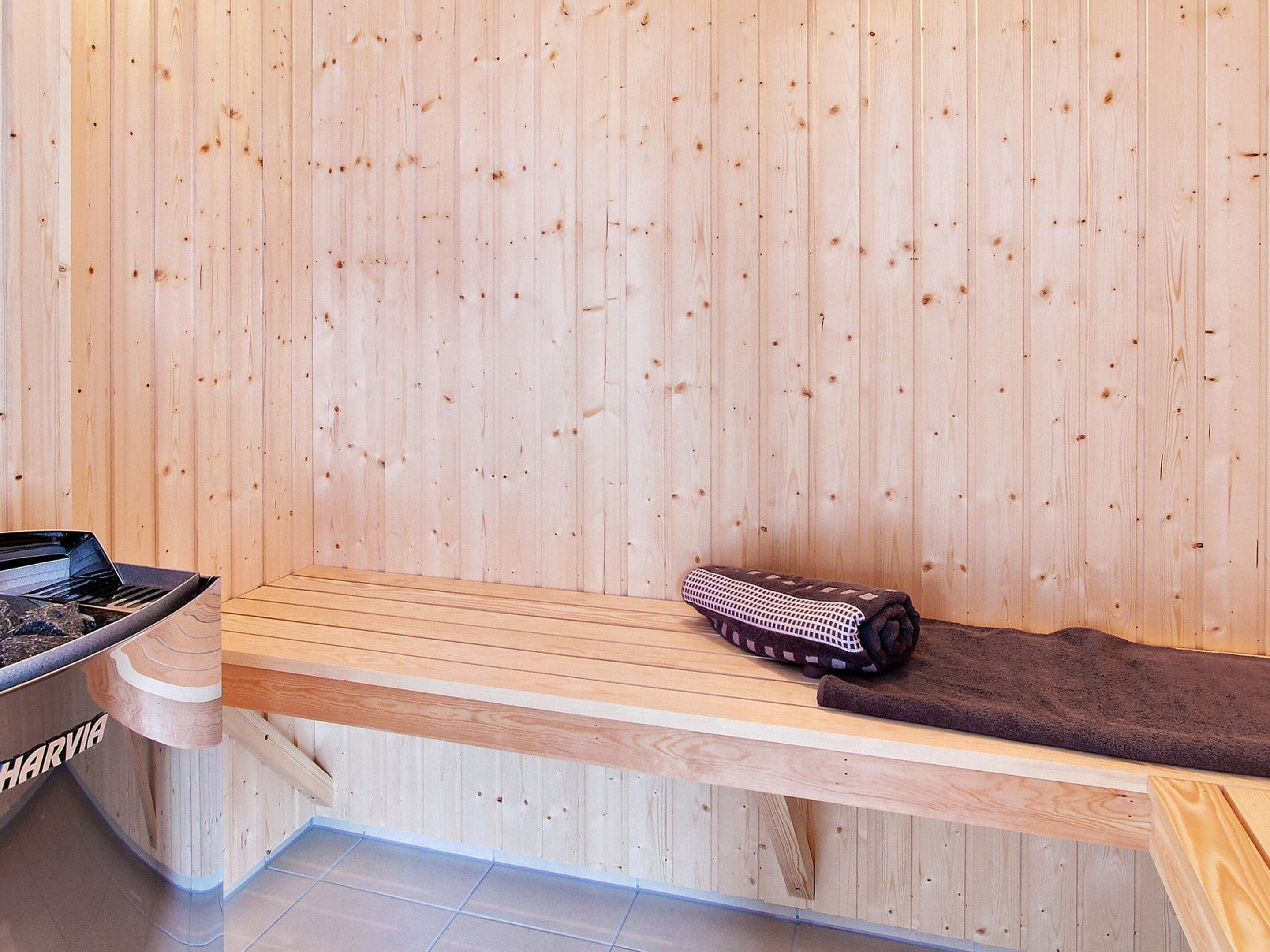 A sauna room with wooden walls, a bench, a towel, and a sauna table.