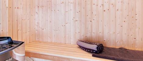Una sala de sauna con paredes de madera, un banco, una toalla y una camilla de sauna.