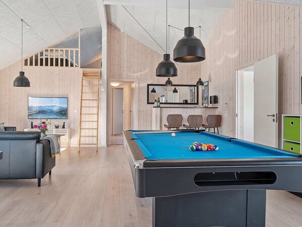 A modern living room with a pool table, wooden walls, and a loft area. - Holiday Home in Kappeln (Kappeln)