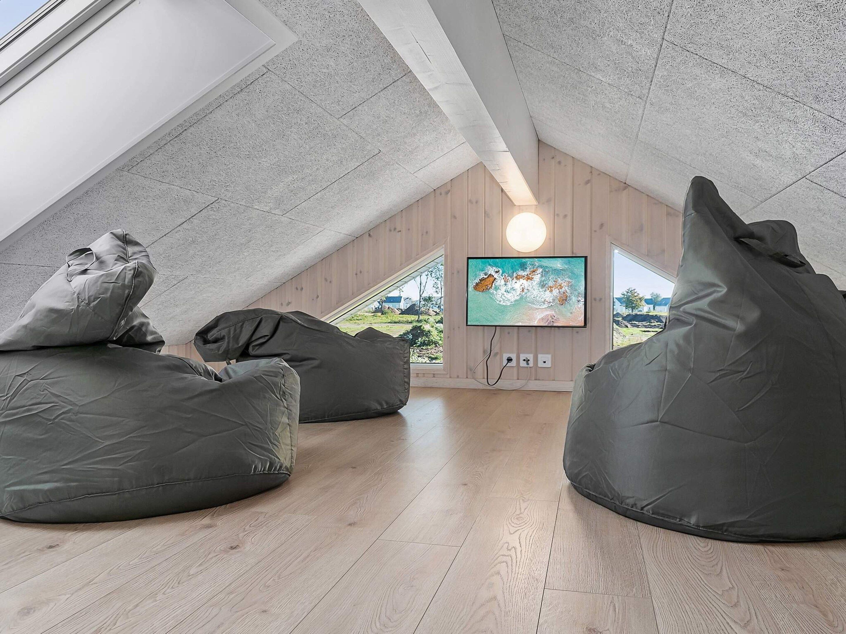 A loft-style room with a sloped ceiling, wooden flooring, and large bean bags.