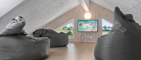 A loft-style room with a sloped ceiling, wooden flooring, and large bean bags.