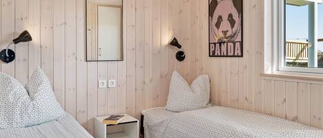 A room with two beds, a mirror, a panda poster, and a window.