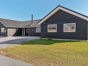 A modern building with a dark exterior, a garage, and a gravel driveway.
