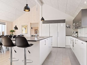 A modern kitchen with white cabinetry, stainless steel appliances, and a central island with bar stools.