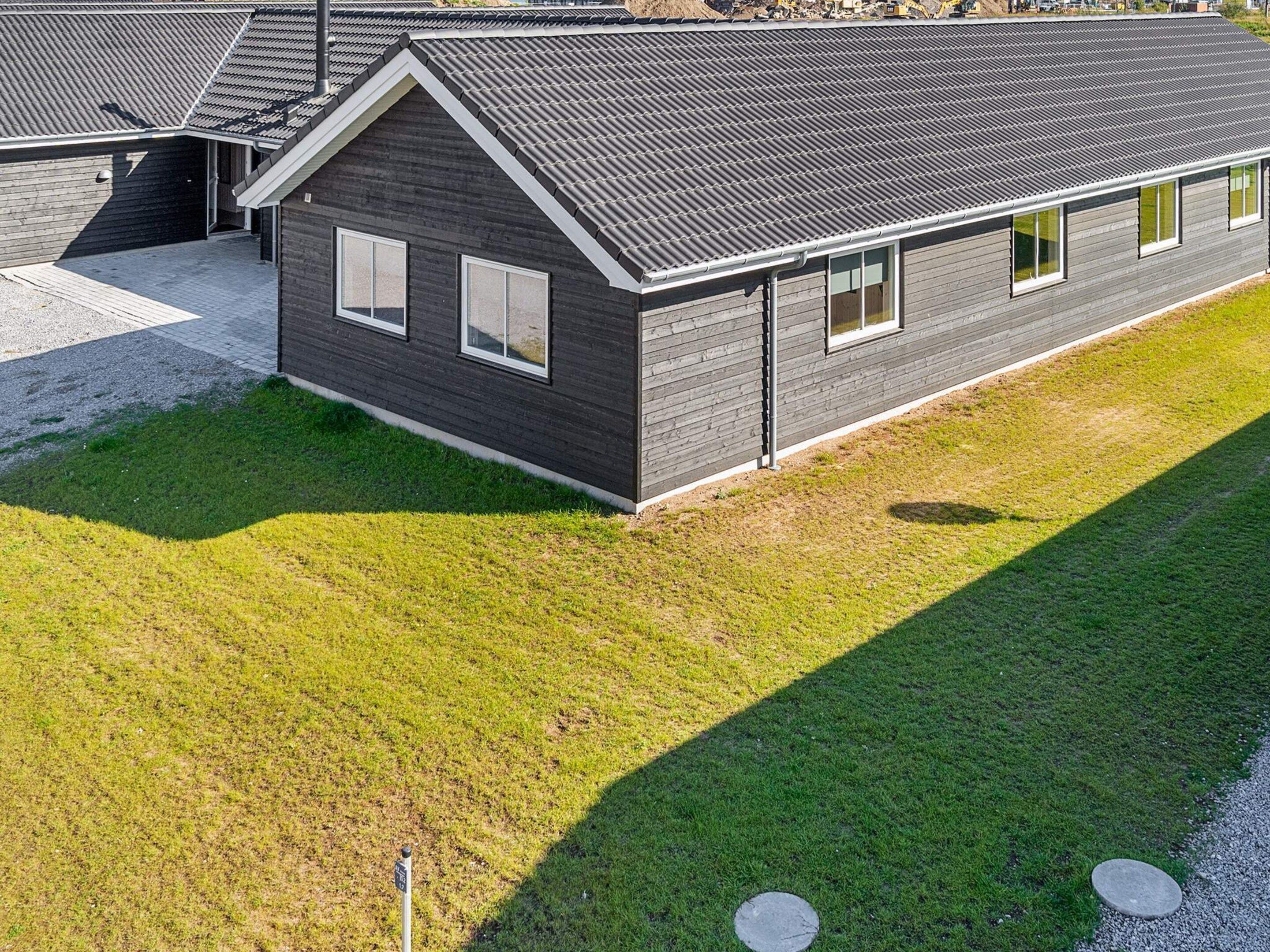 A modern two-story house with a dark exterior, a sloped roof, and a well-maintained lawn.