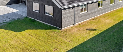 A modern two-story house with a dark exterior, a sloped roof, and a well-maintained lawn.