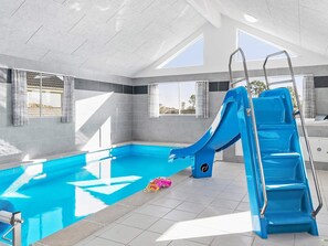 A swimming pool with a blue slide, a ladder, and a toy.