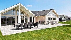 Ett modernt hus med en uteplats, stora fönster och en gräsmatta.