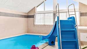 En swimmingpool med en blå vattenrutschkana och en röd leksaksbåt.