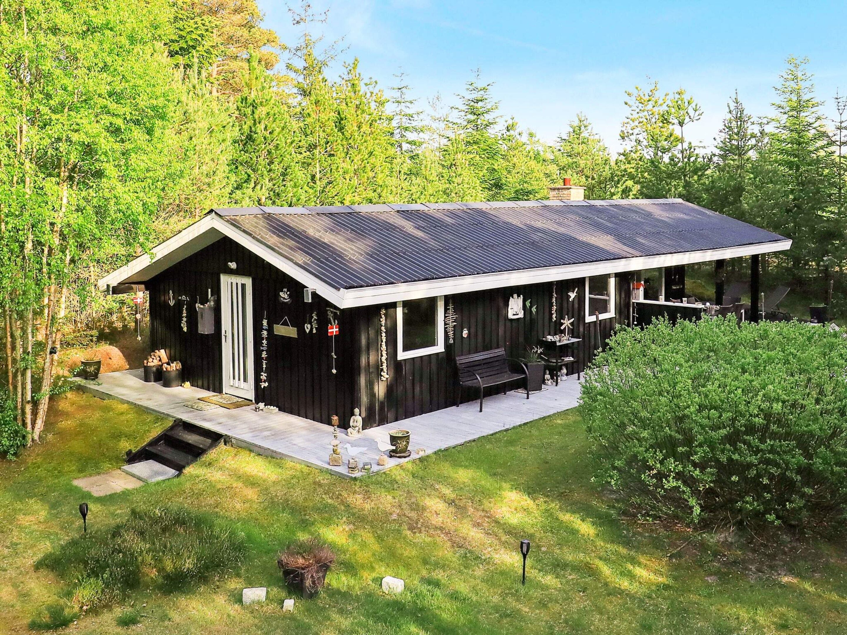 A cabin with a sloped roof, a porch with outdoor seating, and a small deck area.