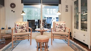 A cozy room with two wicker chairs, a small round table, and a cabinet with glass doors. - 4 Star Holiday Home in Albaek (Aalbaek)