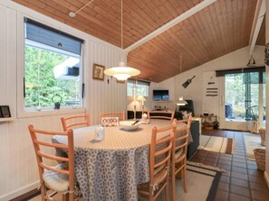 A dining area with a round table, chairs, and a ceiling with wooden beams.