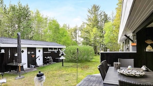 A deck with outdoor furniture, a small shed, and a birdhouse. - 4 Star Holiday Home in Albaek (Aalbaek)