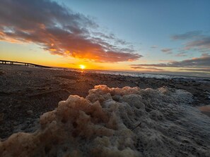A beach with a sunset, a wooden pier, and a rocky foreground. - Seaside Holiday Home with Terrace near Limfjord (Vinderup)