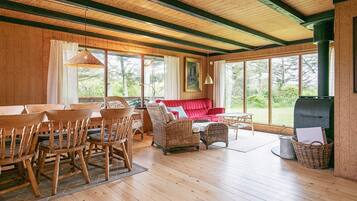 A wooden interior with a dining area, seating, and a fireplace.