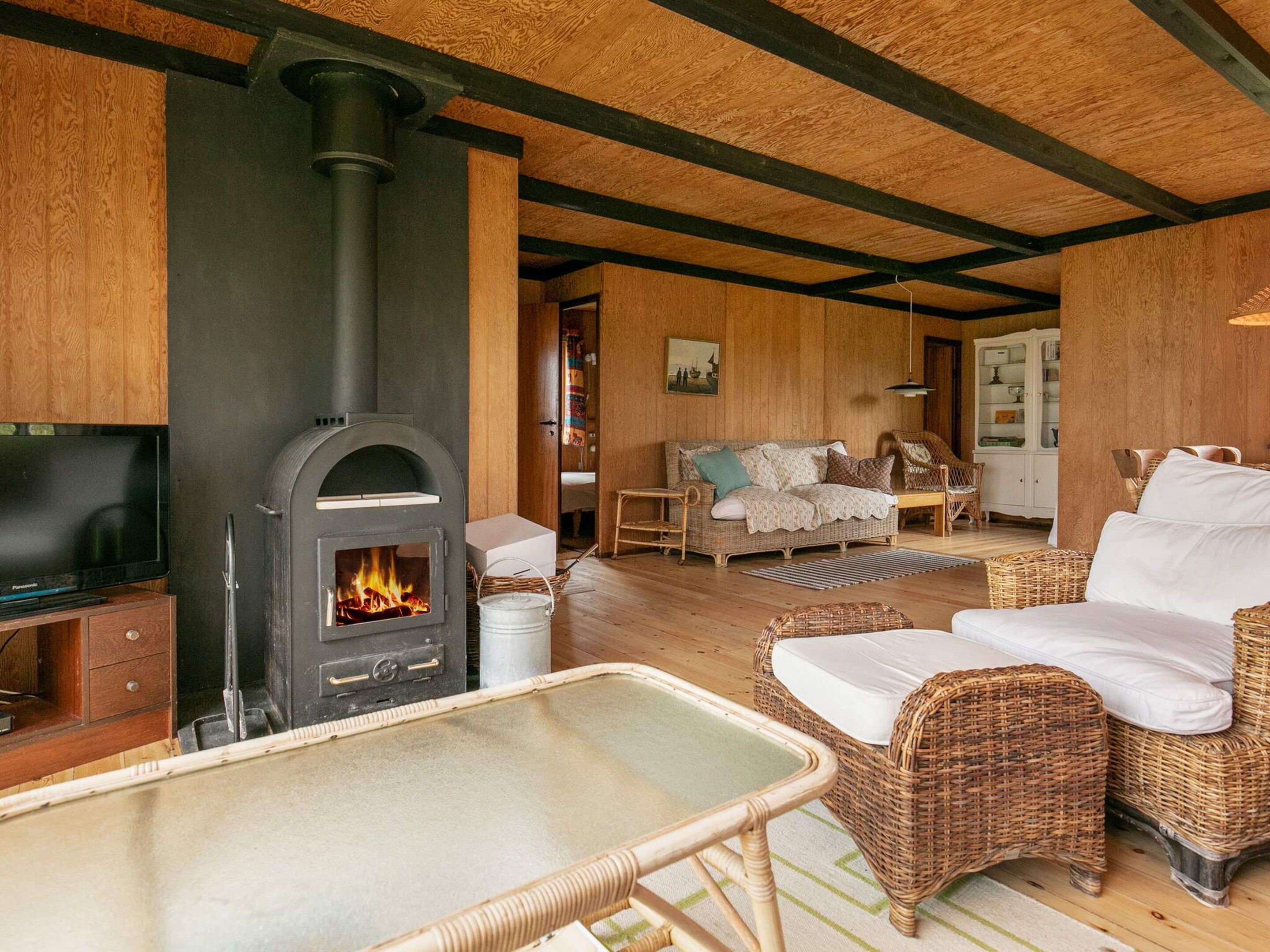 A cozy living room with a fireplace, wicker furniture, and a television.