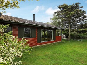 A red wooden house with a chimney, large windows, and a grassy yard. - Seaside Holiday Home with Terrace near Limfjord (Vinderup)