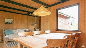 Un intérieur en bois comprenant une table et des chaises, un canapé et une grande fenêtre.