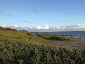 A coastal landscape with grassy hills, a body of water, and a clear sky. - Seaside Holiday Home with Terrace near Limfjord (Vinderup)