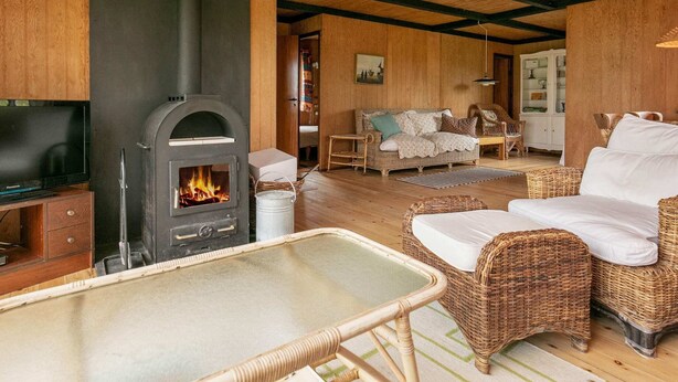 Un salon chaleureux avec un poêle à bois, des meubles en osier et un téléviseur.