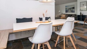 A modern dining area with a white table, two white chairs, and a hanging light fixture. - Enticing Holiday Home in Ebeltoft near Sea (Ebeltoft)