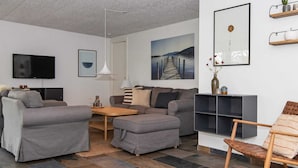 A modern living room with a grey sofa, a wooden coffee table, and a TV mounted on the wall. - Enticing Holiday Home in Ebeltoft near Sea (Ebeltoft)