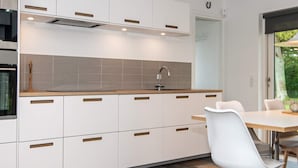 A modern kitchen with white cabinets, a wooden countertop, and a built-in oven. - Enticing Holiday Home in Ebeltoft near Sea (Ebeltoft)