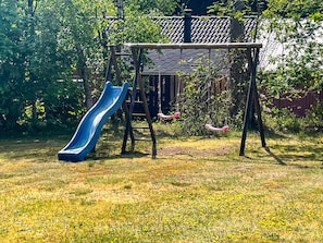 A playground with a blue slide and swings in a grassy area. - Lovely Holiday Home in Jutland near Sea (Hals)