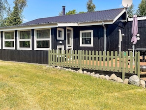 A black wooden house with white trim, a picket fence, and a satellite dish. - Lovely Holiday Home in Jutland near Sea (Hals)