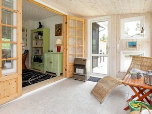 A wooden interior with a dining area, a green cabinet, and a wicker chair. - Lovely Holiday Home in Jutland near Sea (Hals)