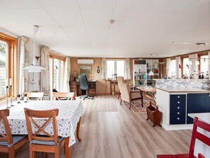 A spacious living area with a dining table, chairs, a kitchen area with a marble countertop, and a bookshelf. - Enticing Holiday Home in FanÃ¸ near Sea (Fano)