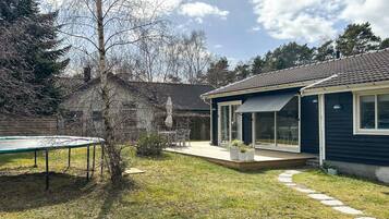 A residential property with a covered patio, a trampoline, and a stone wall.