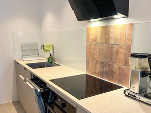 Uma cozinha moderna com forno embutido, máquina de café e pia.