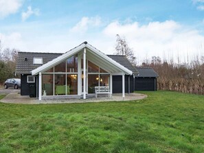A house with a covered patio, a car parked outside, and a grassy yard. - Holiday Home in Ebeltoft (Ebeltoft)