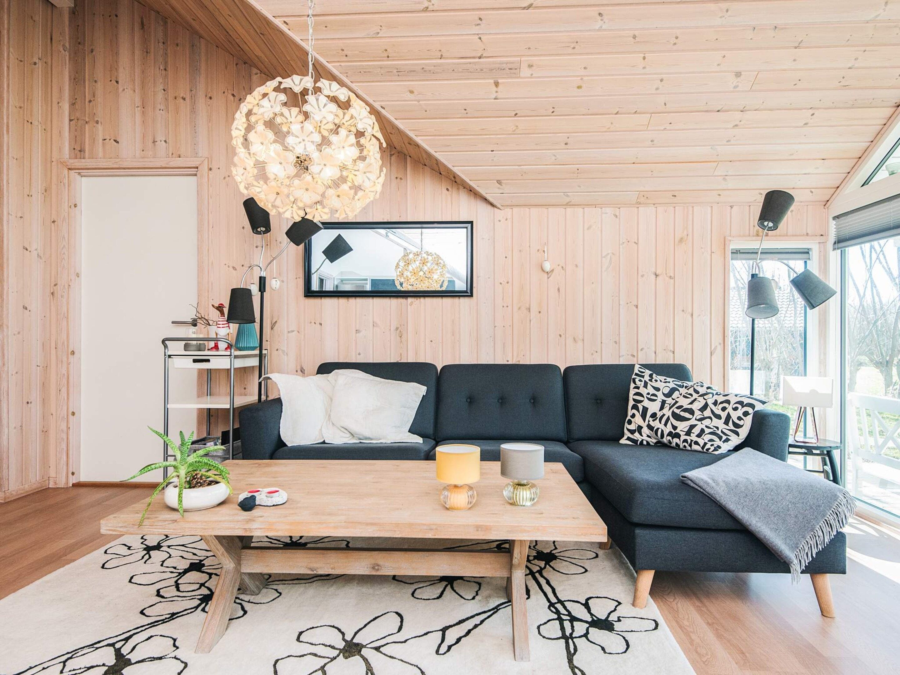 Een moderne woonkamer met een donkerblauwe bank, een houten salontafel en een groot raam.