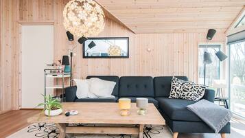 A modern living room with a dark blue sofa, a wooden coffee table, and a large window.