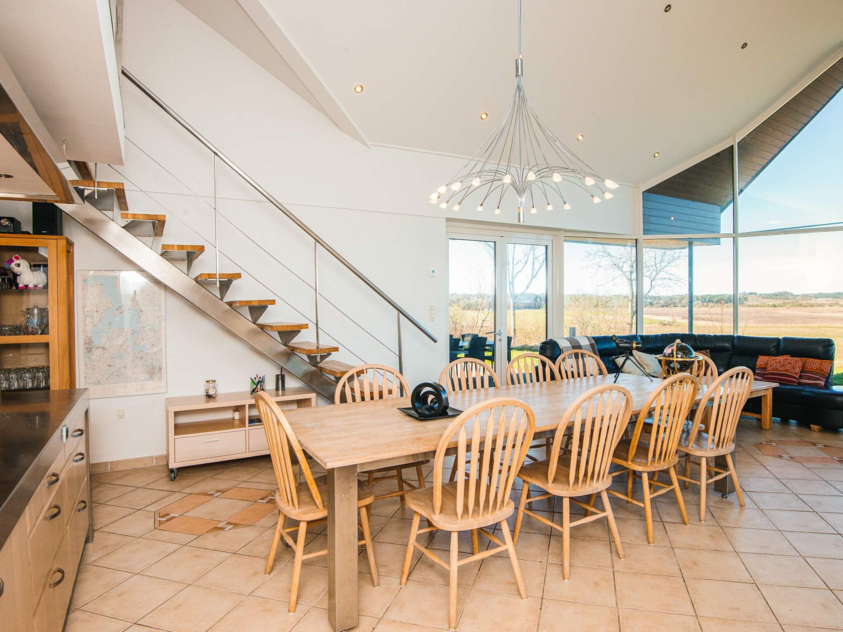 A modern kitchen with a dining area, a staircase, and a view of the outdoors.