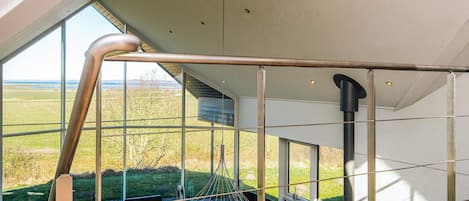 Un interior moderno con barandilla de cristal con vistas a un jardín.