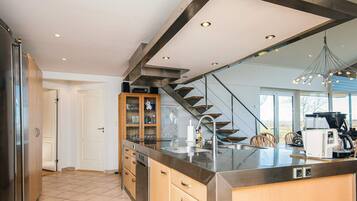 A modern kitchen with a central island, stainless steel appliances, and a wooden cabinet with glass doors.