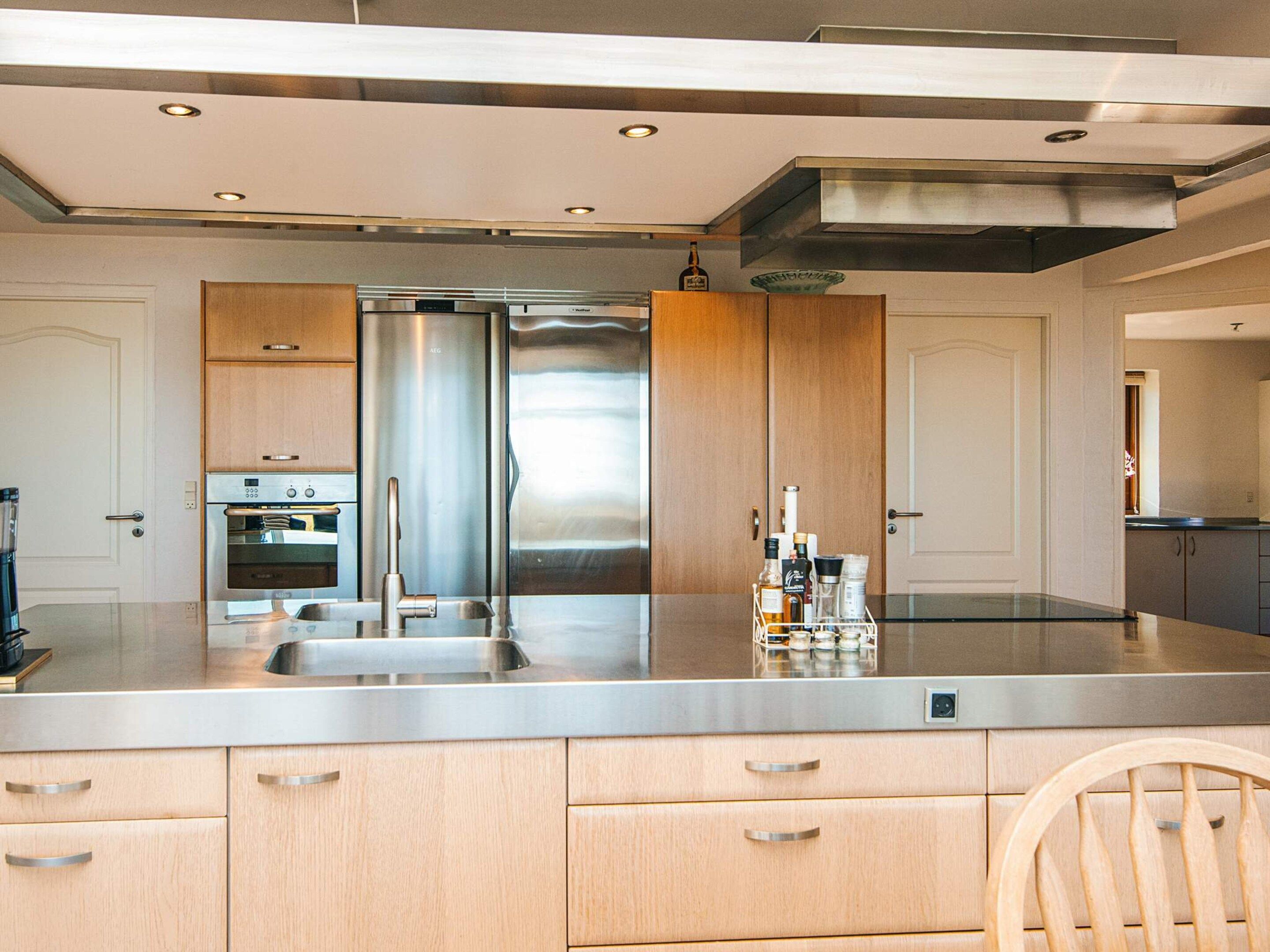 A modern kitchen with stainless steel appliances, wooden cabinets, and a central island with a sink.