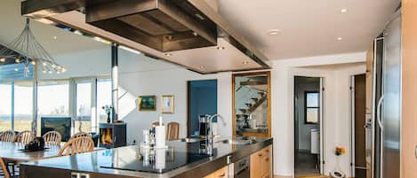 A modern kitchen with a central island, stainless steel appliances, and a large window overlooking a scenic view.