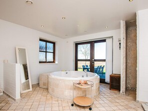 A bathroom with a freestanding bathtub, a mirror, and a window. - 5 Star Holiday Home in Hojslev (Hojslev)