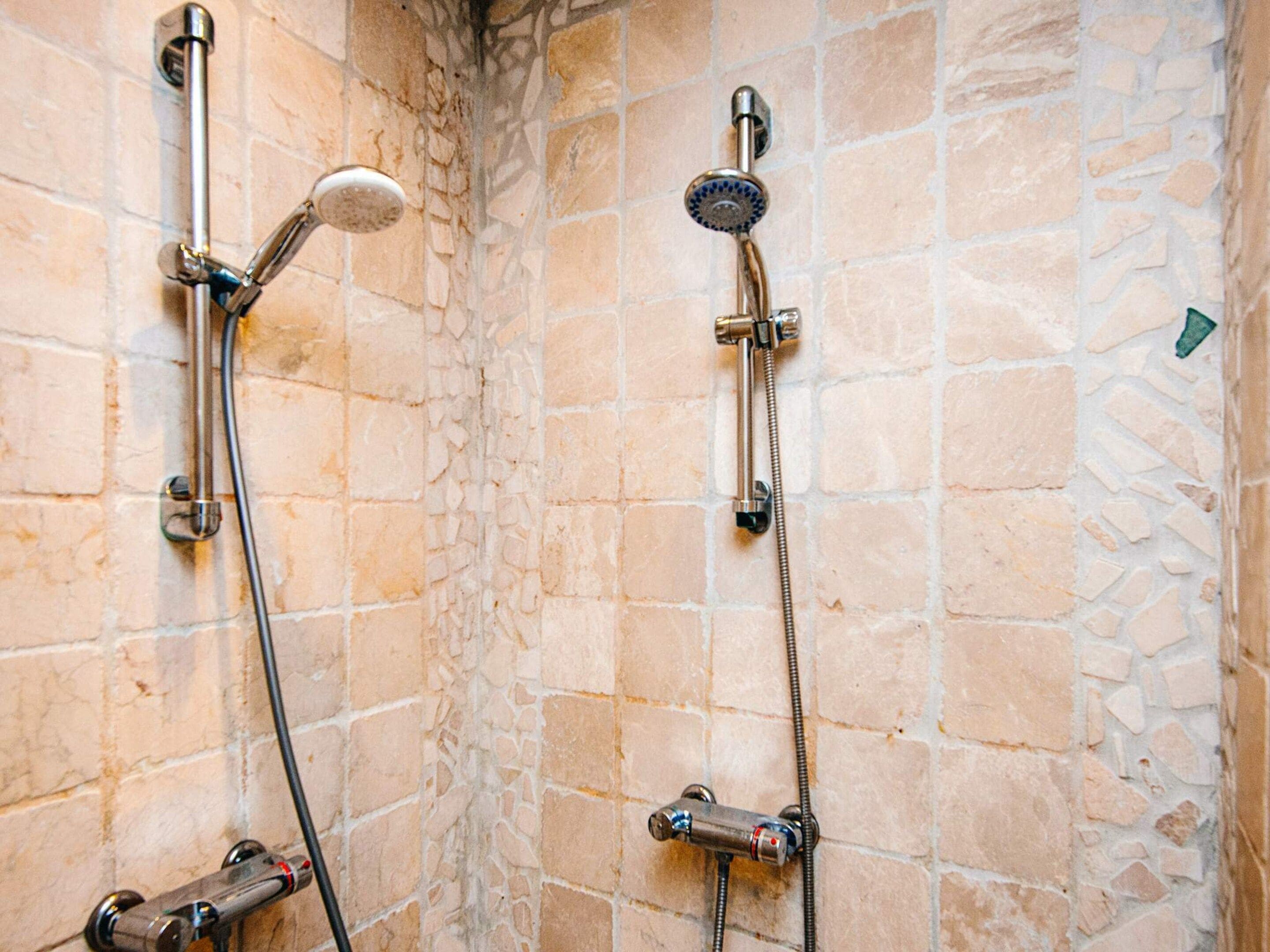 Un espace douche équipé de deux pommes de douche et d’un panneau de commande.