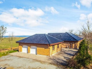 A two-story brick building with a tiled roof, a garage, and a paved driveway. - 5 Star Holiday Home in Hojslev (Hojslev)